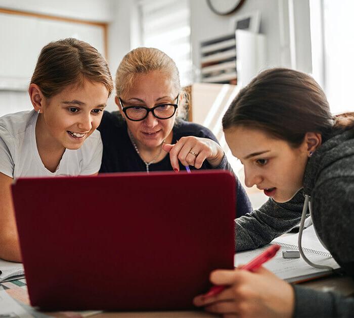 一位母亲和两个女儿正在一起看笔记本电脑